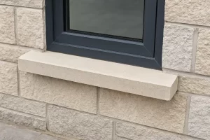 اوکابه یا دست‌انداز پنجره سنگی در نمای ساختمان با قاب آلومینیومی تیره؛ سطح شیب‌دار برای هدایت آب باران و جلوگیری از نفوذ رطوبت به دیوار.