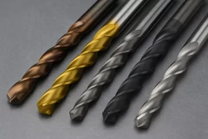 تصویر نزدیک از پنج مته مخصوص فولاد با جنس‌ها و رنگ‌های متفاوت روی سطح فلزی، شامل مته کبالت، تیتانیوم و HSS. 
