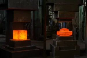 تصویری واقعی از دو فرایند فورجینگ قالب باز و قالب بسته در کارگاه صنعتی؛ در سمت چپ قطعه فلزی بزرگ و داغ در حال فشرده شدن بین قالب‌های تخت (فورج قالب باز) و در سمت راست قطعه‌ای کوچک‌تر درون قالب دارای حفره و شکل‌دهی دقیق (فورج قالب بسته) دیده می‌شود.