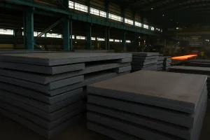 فولادی نورد گرم انباشته‌شده در کارخانه فولاد مبارکه اصفهان با زمینه‌ای از نور گرم و تجهیزات صنعتی
