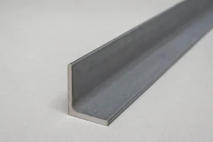 نمای نزدیک از یک نبشی فولادی L شکل با سطح خاکستری و بافت فلزی، قرارگرفته روی پس‌زمینه‌ای روشن و صاف، نشان‌دهنده‌ی جزئیات دقیق سطح و ضخامت نبشی.
