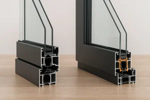 *"مقایسه پنجره آلومینیوم نرمال و ترمال بریک؛ نمای نزدیک از دو نمونه فریم آلومینیومی با شیشه دوجداره، که در مدل ترمال بریک نوار عایق پلی‌آمید نارنجی رنگ دیده می‌شود."**
