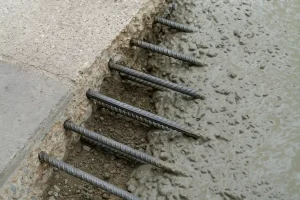 اتصال بتن قدیم به جدید با استفاده از میلگردهای کاشته‌شده در بتن قدیمی و بتن تازه‌ریزی‌شده در کنار آن، نمایش جزئیات فنی اجرای پیوند مکانیکی بین دو سطح بتنی.